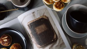 A rustic breakfast arrangement with pastries, tea, and a vintage book in a cozy still life composition.